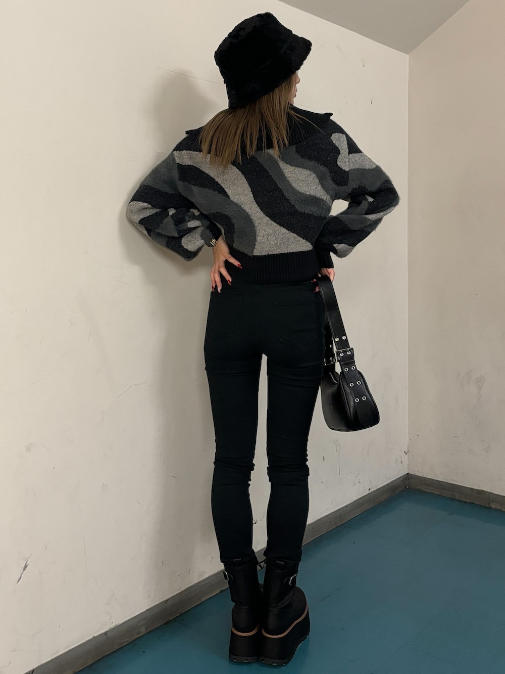 ブラック系のニット/セーター、ブラック系のハンドバッグ、ブラック系のブーツを着用したレディースの秋コーディネートの3枚目の写真