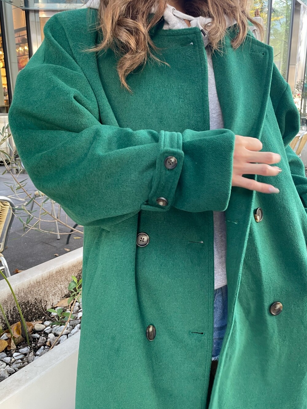 グリーン系のチェスターコート、ブラック系のブーツを着用したレディースの秋コーディネートの7枚目の写真