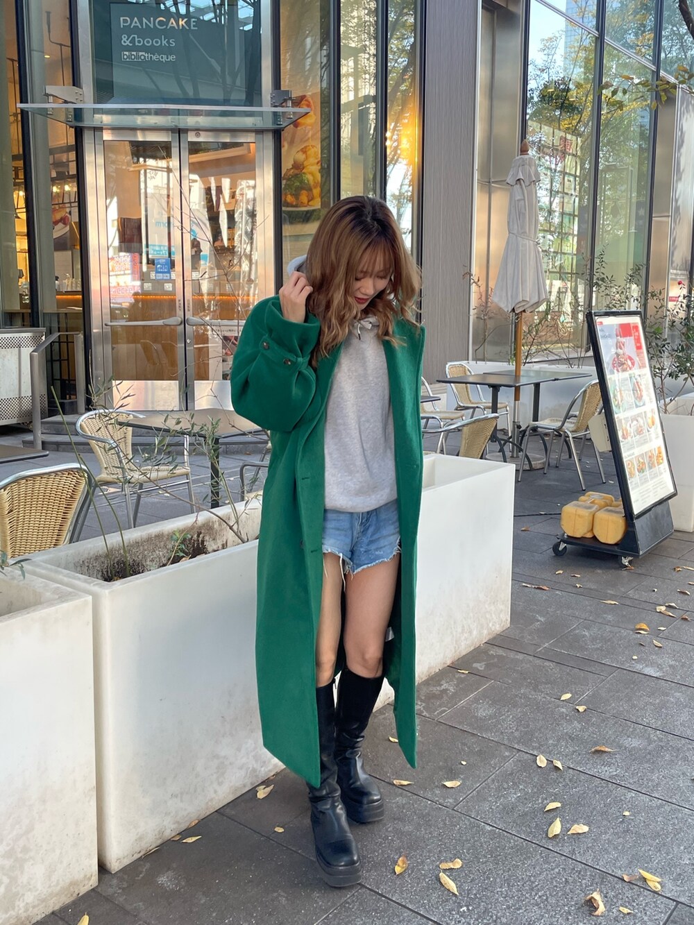 グリーン系のチェスターコート、ブラック系のブーツを着用したレディースの秋コーディネートの6枚目の写真