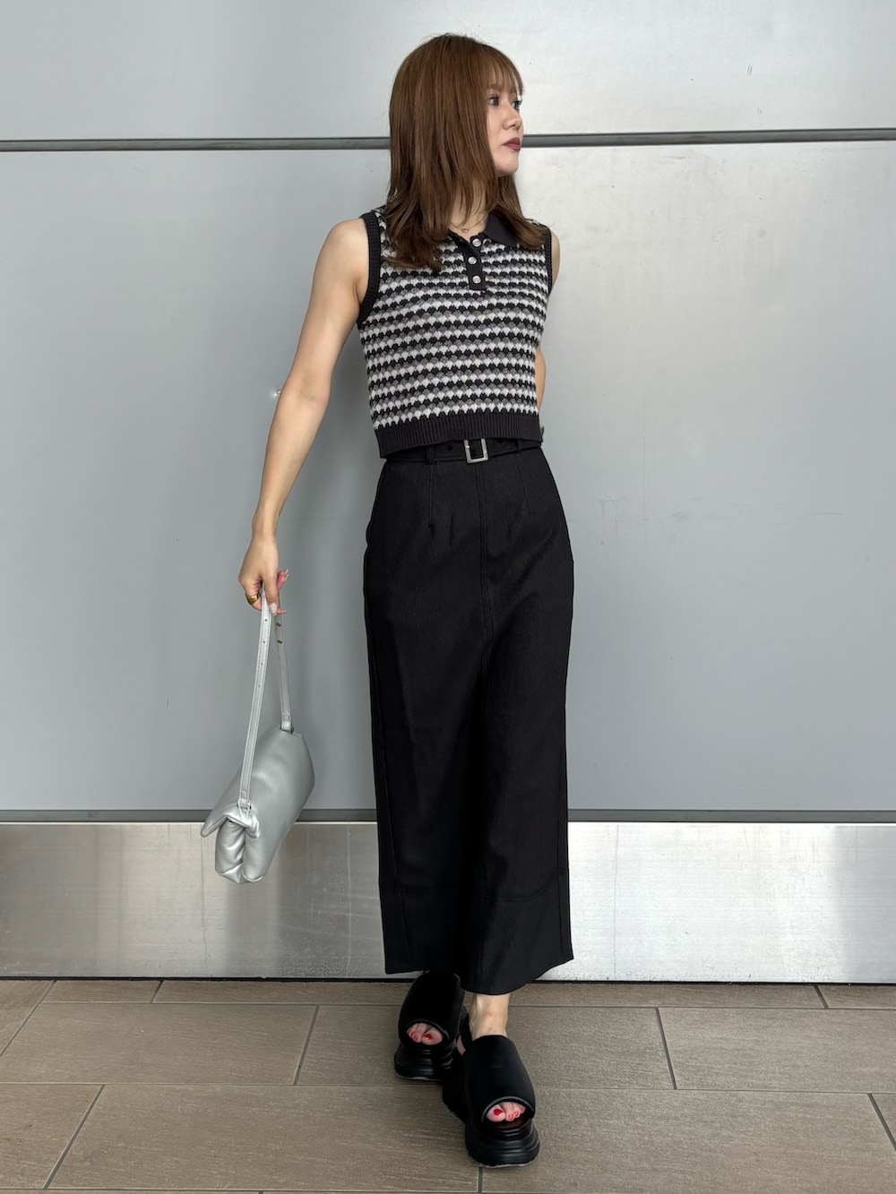 グレー系のニット/セーター、シルバー系のハンドバッグ、ブラック系のスカートを着用したレディースの夏コーディネートの4枚目の写真