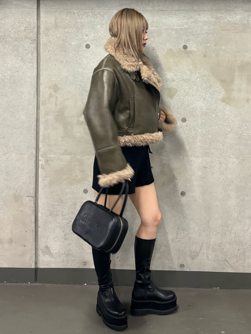 ブラック系のその他パンツ、ブラック系のブーツ、グリーン系のムートンコートを着用したレディースの夏コーディネートの4枚目の写真
