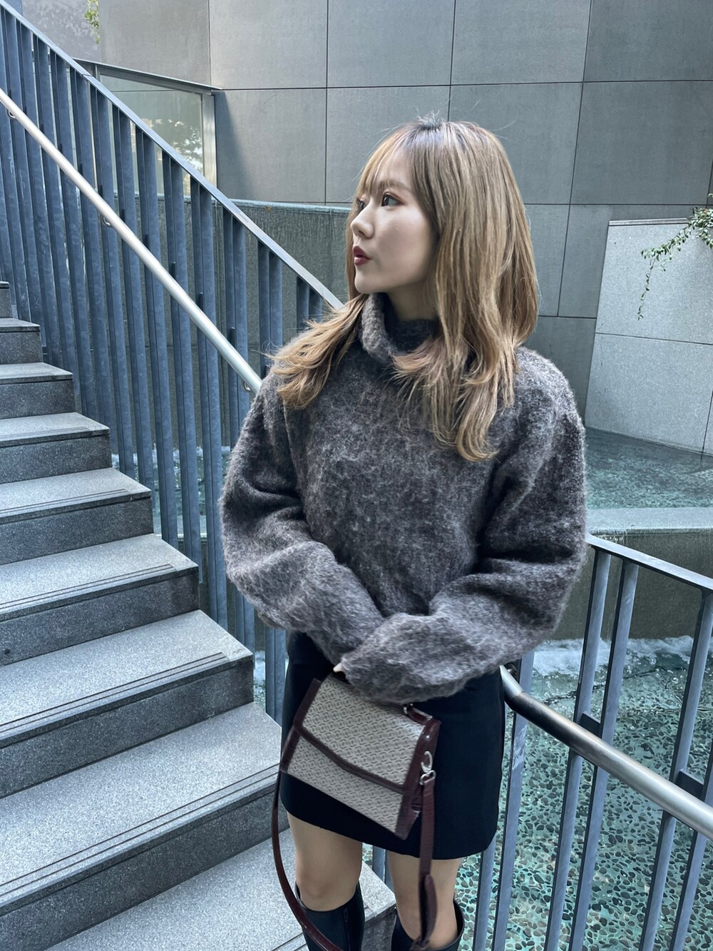 ブラウン系のニット/セーター、ブラック系のスカート、その他のハンドバッグを着用したレディースの秋コーディネートの3枚目の写真