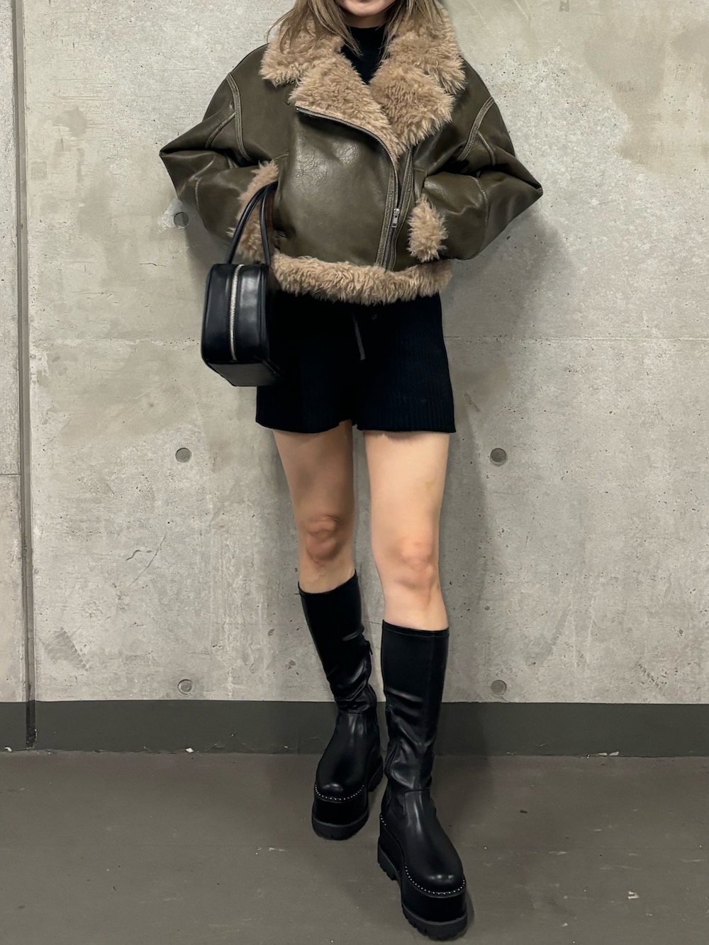 ブラック系のその他パンツ、ブラック系のブーツ、グリーン系のムートンコートを着用したレディースの夏コーディネートの3枚目の写真