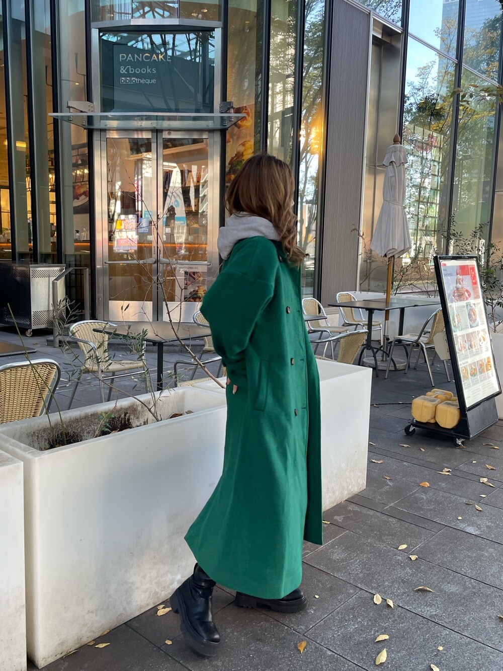 グリーン系のチェスターコート、ブラック系のブーツを着用したレディースの秋コーディネートの2枚目の写真