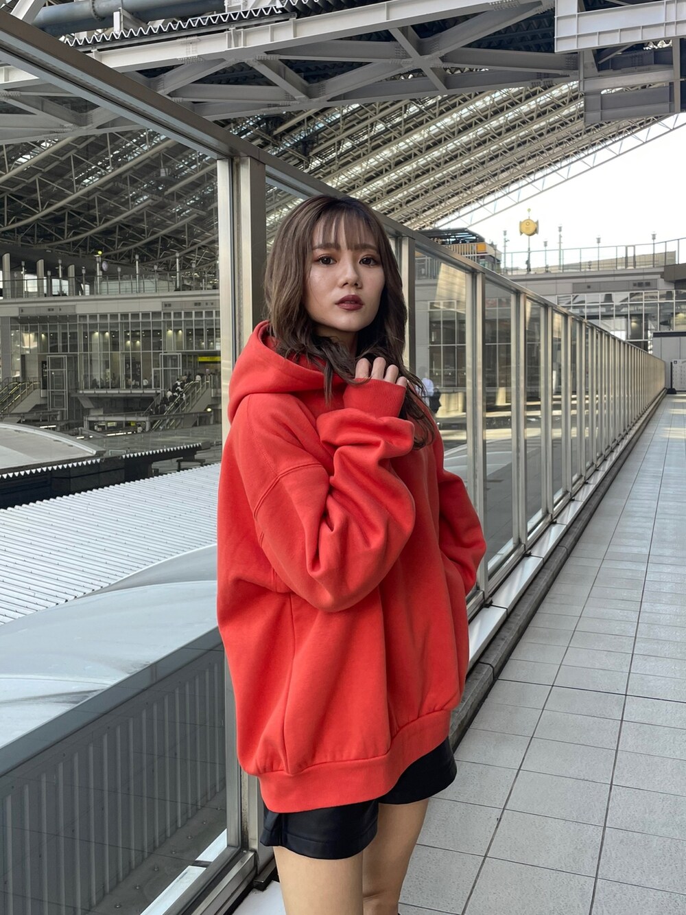 オレンジ系のパーカー、ブラック系のブーツを着用したレディースの秋コーディネートの3枚目の写真