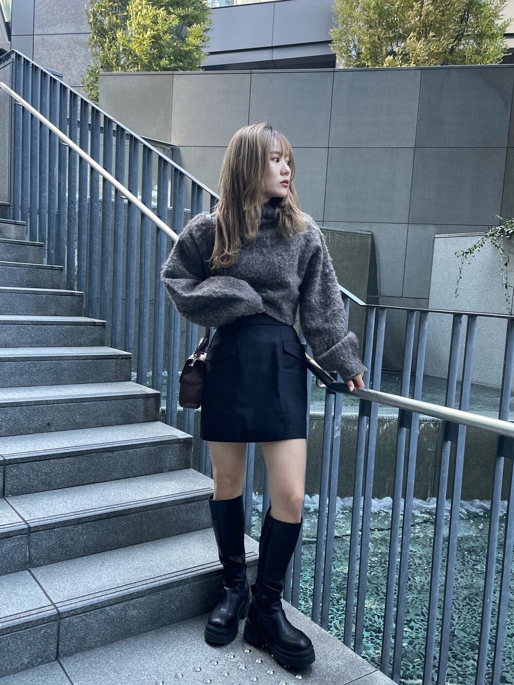 ブラウン系のニット/セーター、ブラック系のスカート、その他のハンドバッグを着用したレディースの秋コーディネートの2枚目の写真