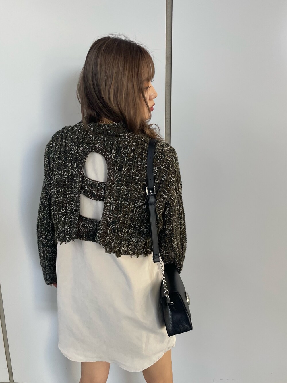 グリーン系のワンピース、ブラック系のショルダーバッグ、ブラック系のブーツを着用したレディースの秋コーディネートの5枚目の写真