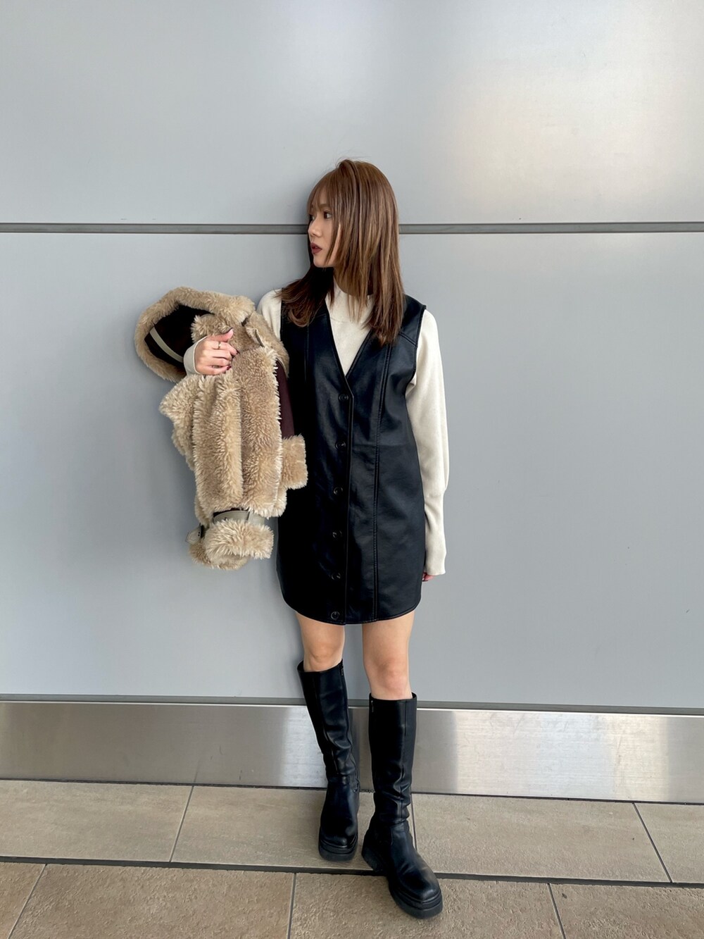 ブラック系のワンピース、ホワイト系のニット/セーター、ブラウン系のムートンコートを着用したレディースの冬コーディネートの7枚目の写真