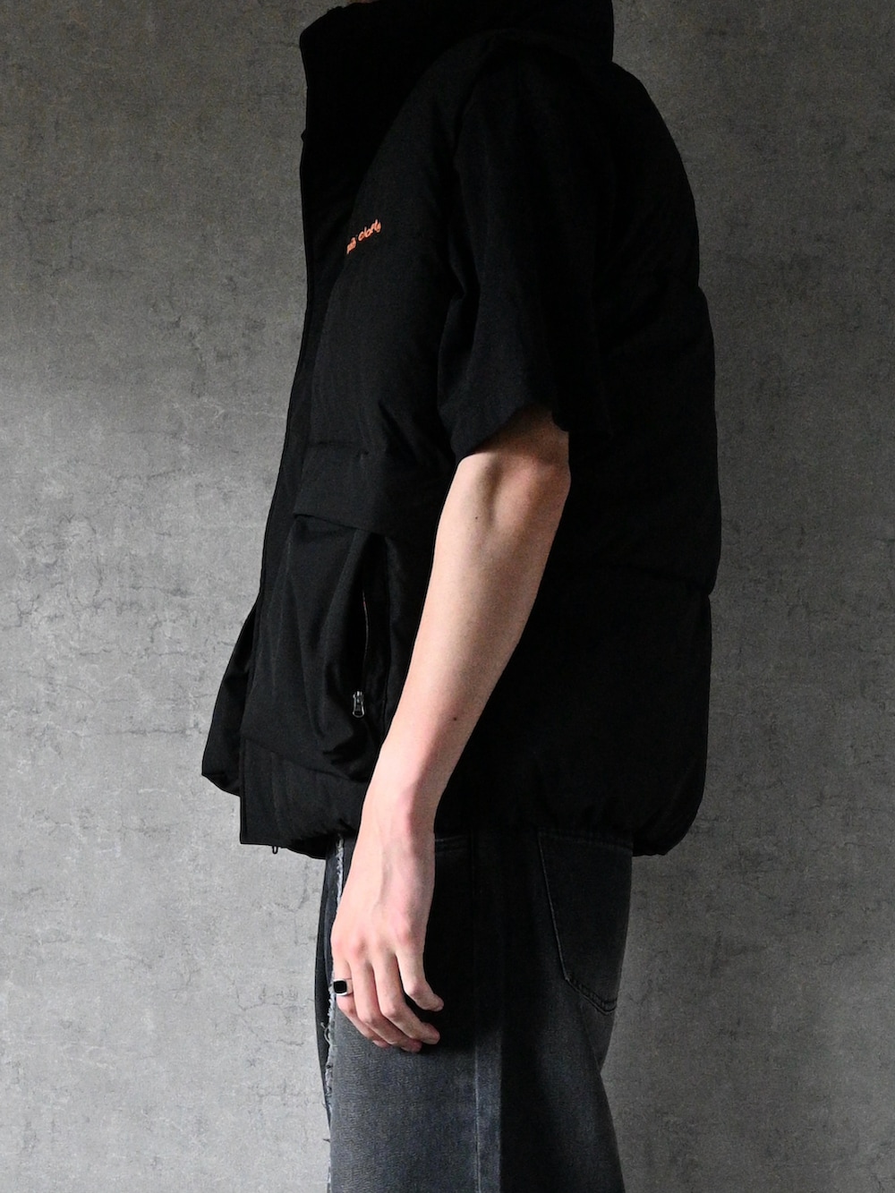 ブラック系のダウンベスト、ブラック系のスニーカー、ブラック系のデニムパンツを着用したメンズの秋コーディネートの2枚目の写真