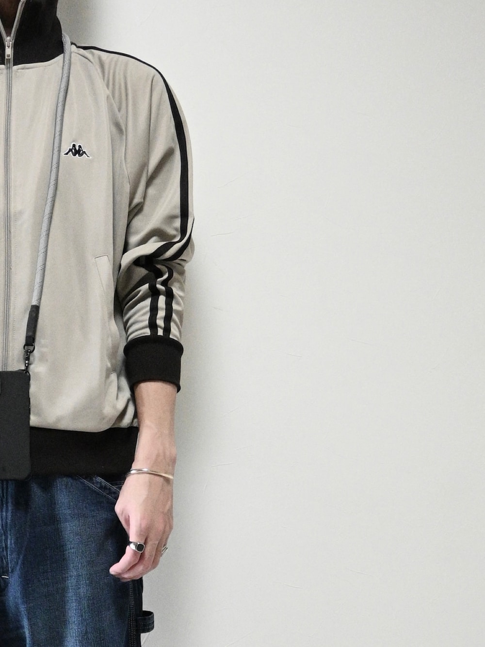 ベージュ系のジャージ、ブルー系のデニムパンツ、ブラック系のスニーカーを着用したメンズの秋コーディネートの2枚目の写真