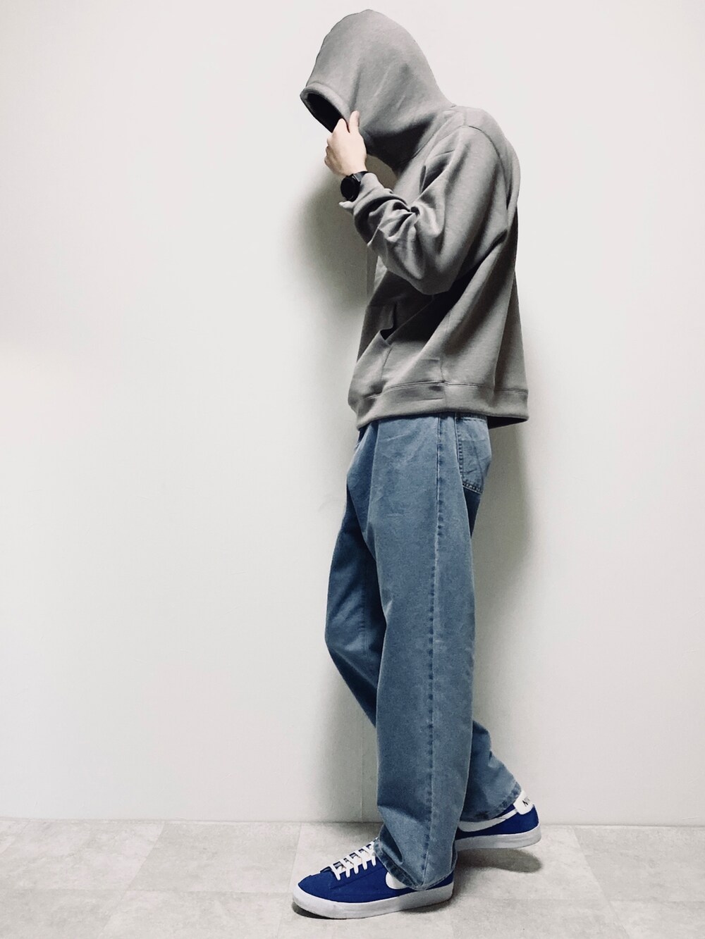 グレー系のパーカー、ブルー系のデニムパンツ、ブルー系のスニーカーを着用したメンズの冬コーディネートの2枚目の写真