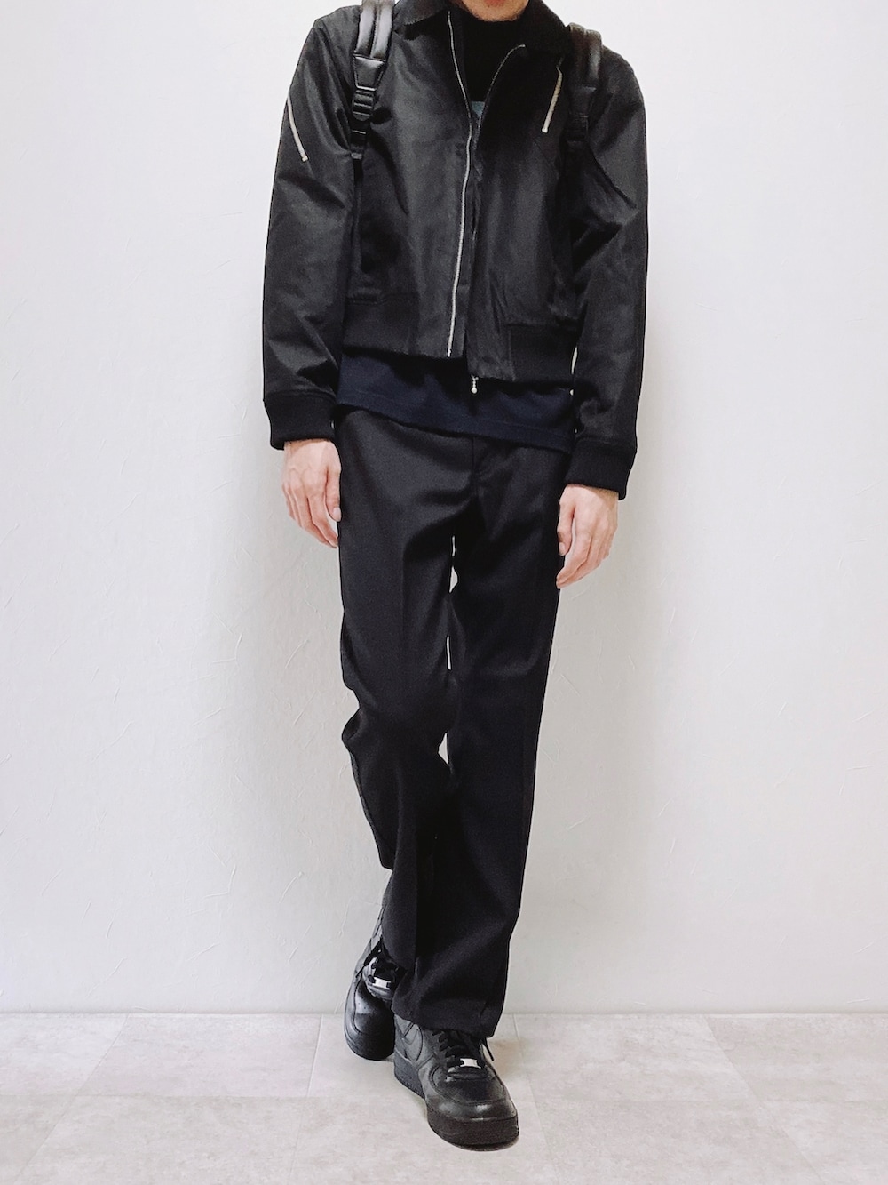 ブラック系のブルゾン、ブラック系のスラックス、ブラウン系のバックパック/リュックを着用したメンズの春コーディネートの3枚目の写真