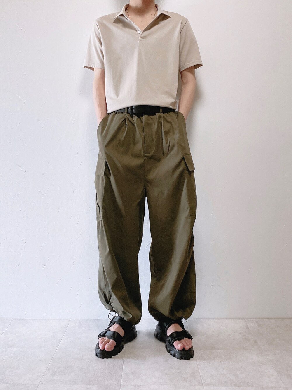 グリーン系のカーゴパンツ、グレー系のポロシャツ、ブラック系のサンダルを着用したメンズの夏コーディネートの2枚目の写真