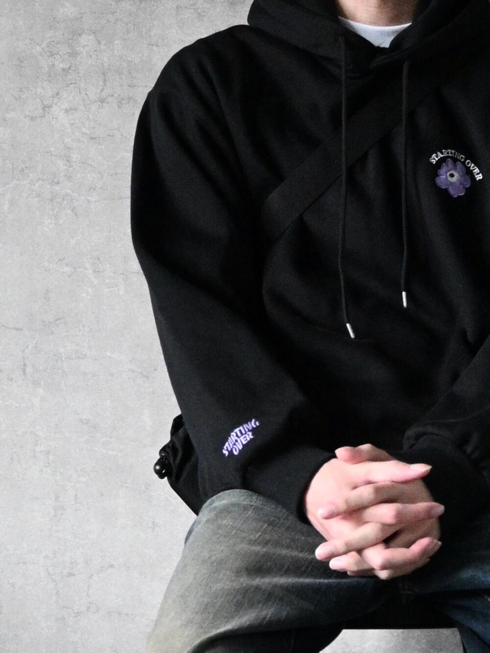 ブラック系のパーカー、ブラック系のスニーカー、ブルー系のデニムパンツを着用したメンズの春コーディネートの2枚目の写真