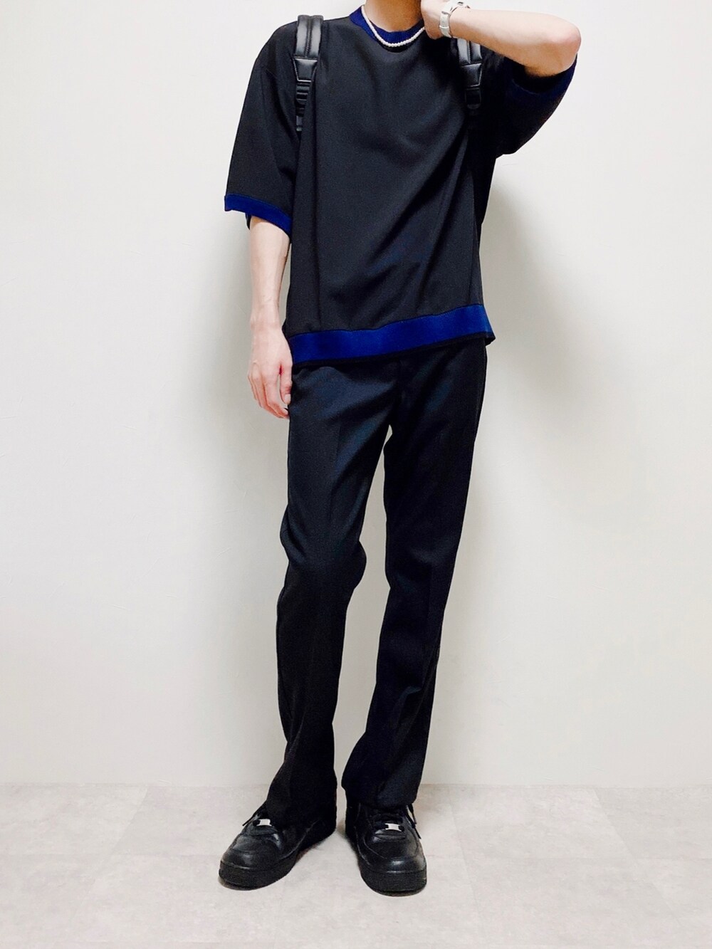 ブラック系のスラックス、ブラウン系のバックパック/リュック、ブラック系のTシャツ/カットソーを着用したメンズの春コーディネートの3枚目の写真