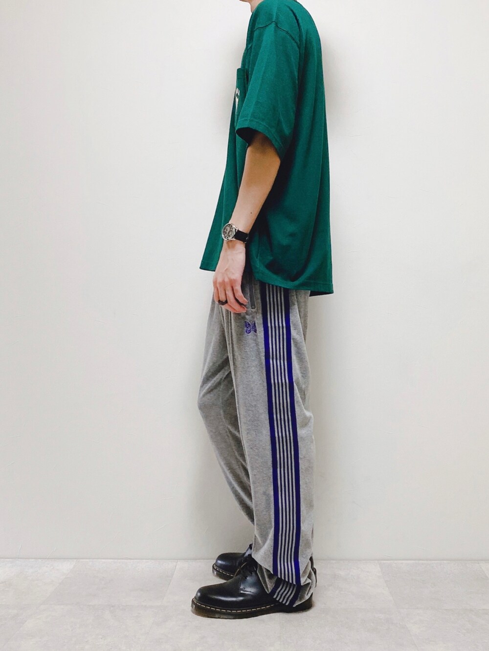 グリーン系のTシャツ/カットソー、グレー系のパンツ、ブラウン系のバックパック/リュックを着用したメンズの春コーディネートの2枚目の写真