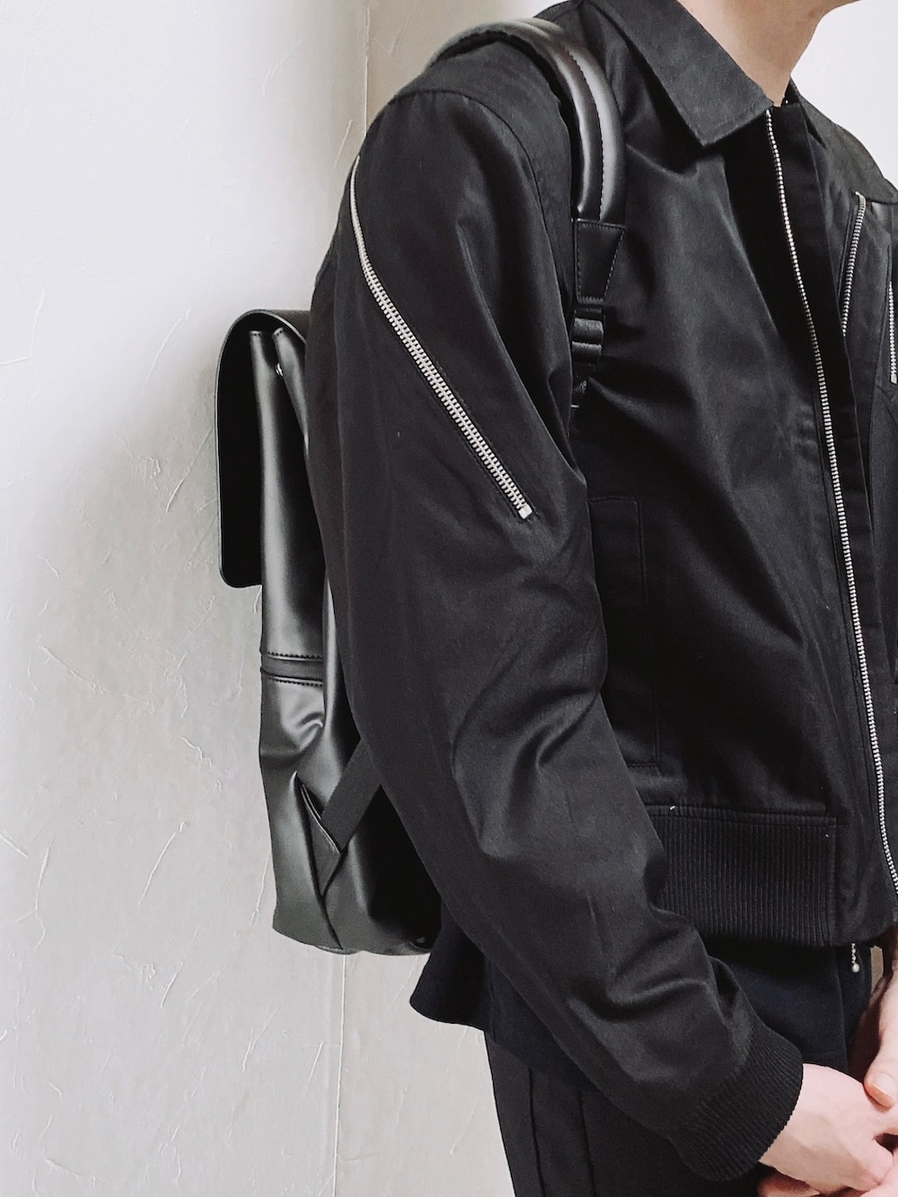 ブラック系のブルゾン、ブラック系のスラックス、ブラウン系のバックパック/リュックを着用したメンズの春コーディネートの2枚目の写真