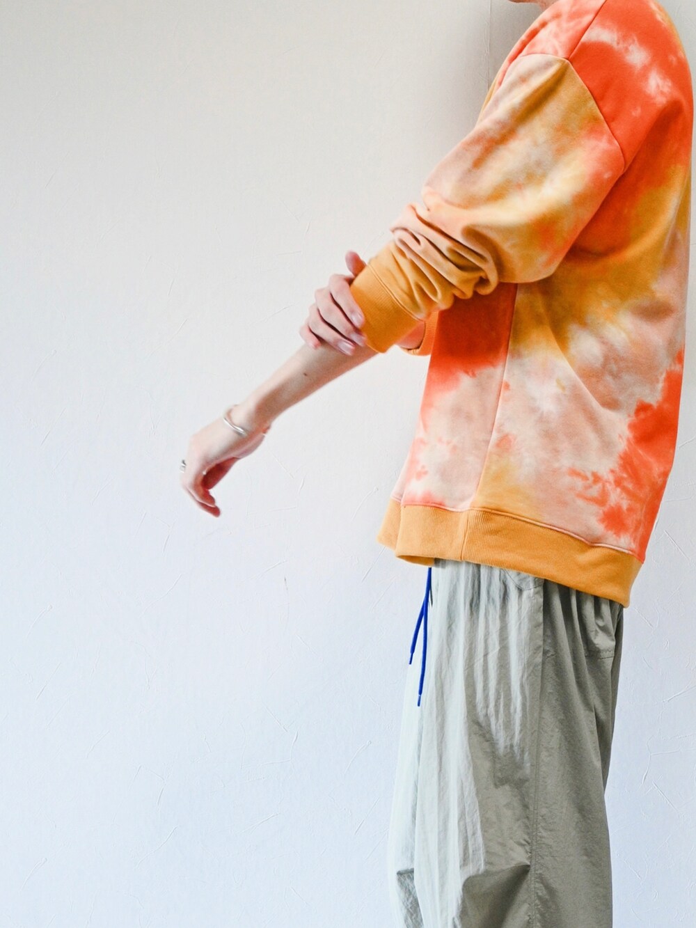 オレンジ系のスウェット、グレー系のその他パンツ、ブラック系のスニーカーを着用したメンズの春コーディネートの2枚目の写真