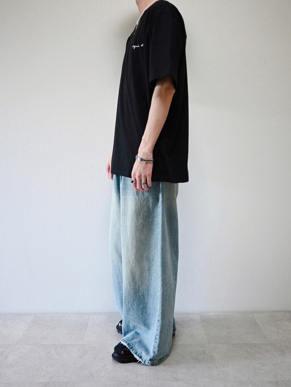 ブラック系のTシャツ/カットソー、ブルー系のデニムパンツ、シルバー系のブレスレットを着用したメンズの夏コーディネートの2枚目の写真