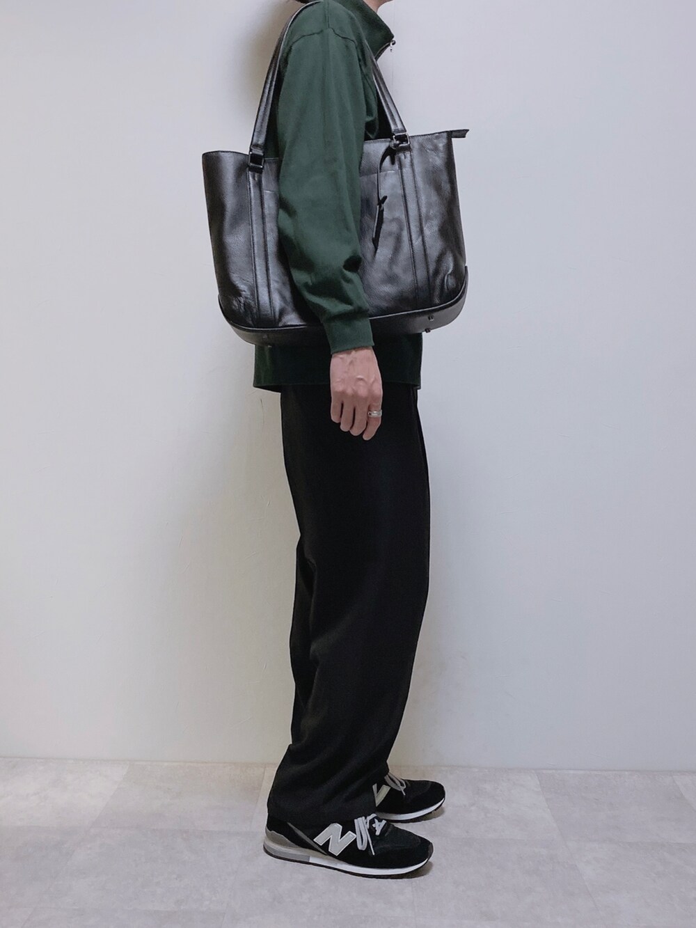 ブラック系のスラックス、グリーン系のTシャツ/カットソー、ブラック系のスニーカーを着用したメンズの秋コーディネートの2枚目の写真