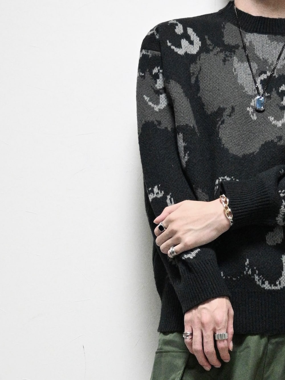 ブラック系のニット/セーター、グリーン系のカーゴパンツ、ブラック系のスニーカーを着用したメンズの秋コーディネートの2枚目の写真