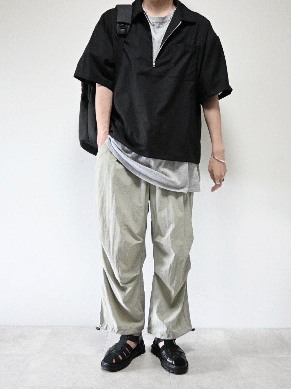 ブラック系のシャツ/ブラウス、ブラック系のバックパック/リュック、グレー系のその他パンツを着用したメンズの夏コーディネートの2枚目の写真