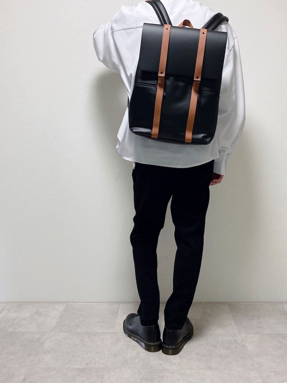 ブラウン系のバックパック/リュック、ホワイト系のシャツ/ブラウス、ブラック系のスラックスを着用したメンズの春コーディネートの2枚目の写真