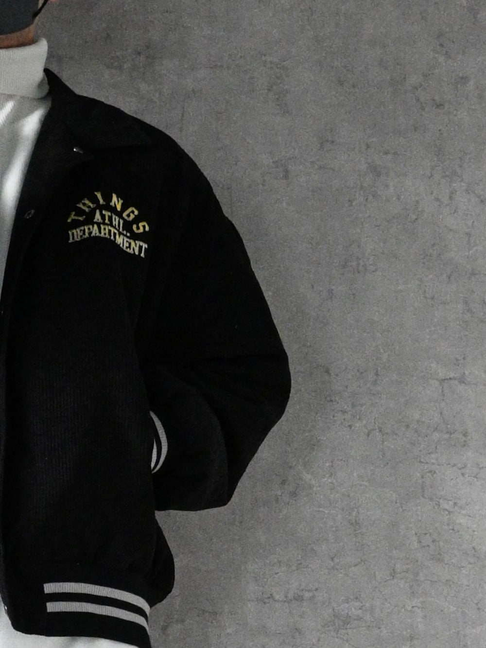 ブラック系のスタジャン、ホワイト系のニット/セーター、ブラック系のパンツを着用したメンズの冬コーディネートの2枚目の写真