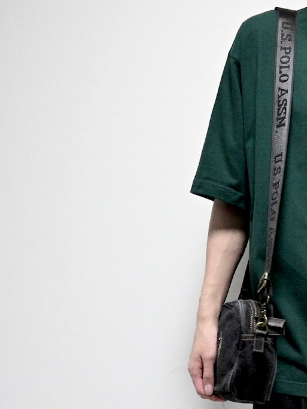 ブラック系のショルダーバッグ、グリーン系のTシャツ/カットソー、シルバー系のブレスレットを着用したメンズの夏コーディネートの2枚目の写真