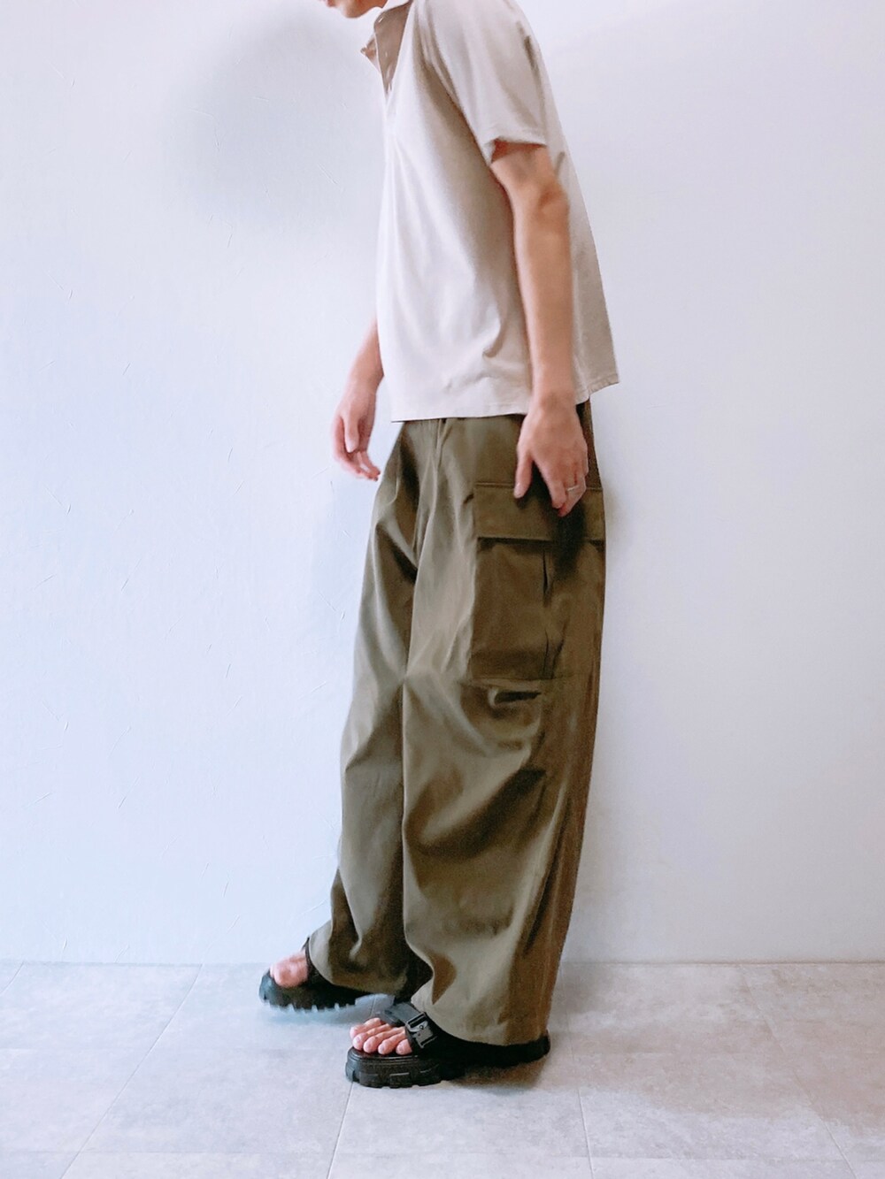 グリーン系のカーゴパンツ、グレー系のポロシャツ、ブラック系のサンダルを着用したメンズの夏コーディネートの2枚目の写真