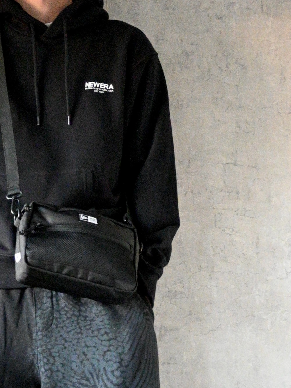 ブラック系のパーカー、ブラック系のスウェットパンツ、ブラック系のショルダーバッグを着用したメンズの冬コーディネートの2枚目の写真