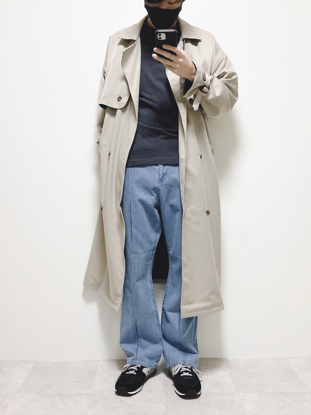 ブルー系のスラックス、ベージュ系のトレンチコート、ブラック系のTシャツ/カットソーを着用したメンズの冬コーディネートの2枚目の写真