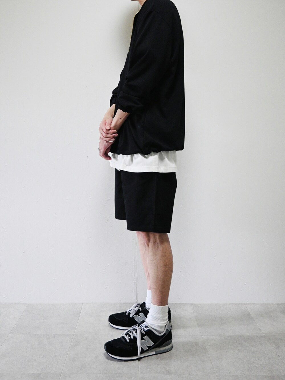 ブラック系のチノパンツ、ブラック系のTシャツ/カットソー、ブラック系のスニーカーを着用したメンズの春コーディネートの2枚目の写真