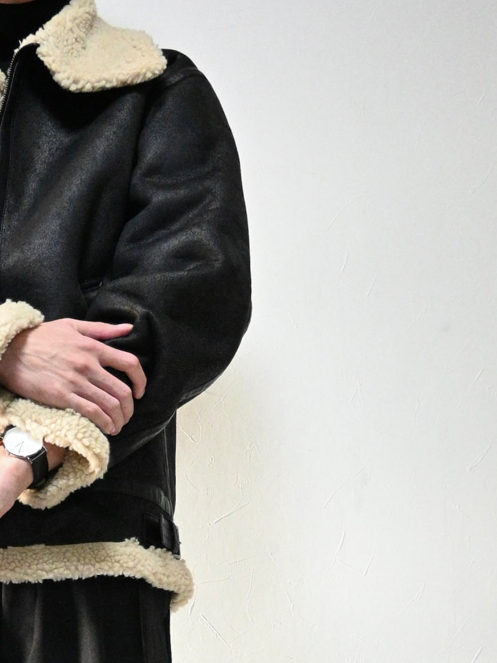 ブラック系のムートンコート、シルバー系の腕時計、シルバー系のネックレスを着用したメンズの冬コーディネートの2枚目の写真