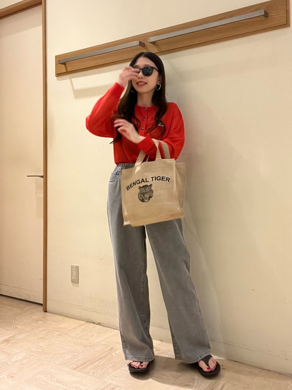 グレー系のデニムパンツ、レッド系のカーディガン/ボレロ、ベージュ系のトートバッグを着用したレディースの春コーディネートの6枚目の写真