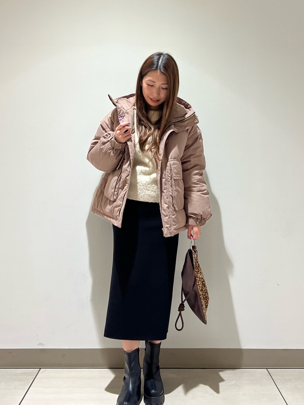 ブラウン系のダウンジャケット/コート、ホワイト系のニット/セーター、ブラック系のスカートを着用したレディースの冬コーディネートの4枚目の写真