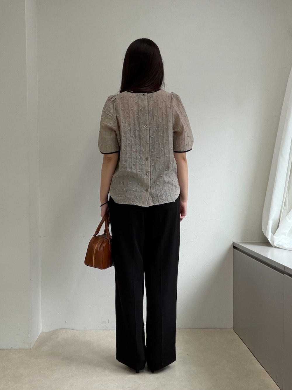 ベージュ系のシャツ/ブラウス、ブラック系のスラックス、ブラック系のパンプスを着用したレディースの春コーディネートの3枚目の写真