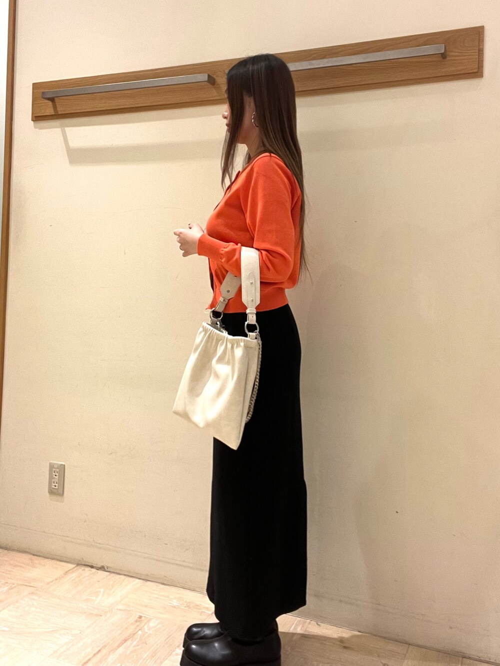 オレンジ系のカーディガン/ボレロ、ブラック系のスカートを着用したレディースの春コーディネートの3枚目の写真