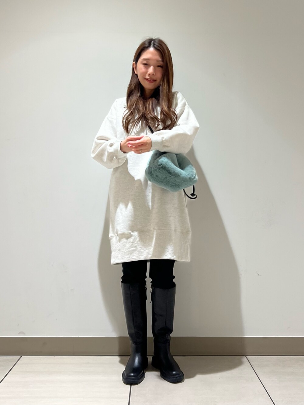 ホワイト系のワンピース、グリーン系のショルダーバッグ、ブラック系のブーツを着用したレディースの冬コーディネートの3枚目の写真