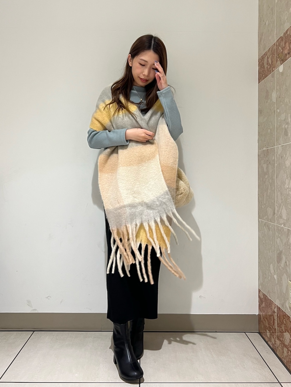 グリーン系のTシャツ/カットソー、ブラック系のスカート、ブラック系のブーツを着用したレディースの冬コーディネートの2枚目の写真