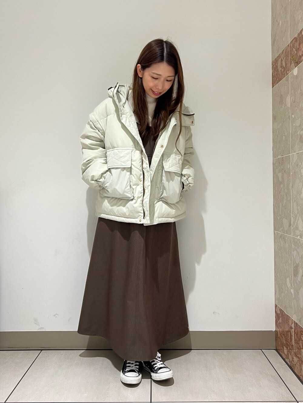 グレー系のダウンジャケット/コート、ブラウン系のジャンパースカート、ホワイト系のTシャツ/カットソーを着用したレディースの冬コーディネートの2枚目の写真