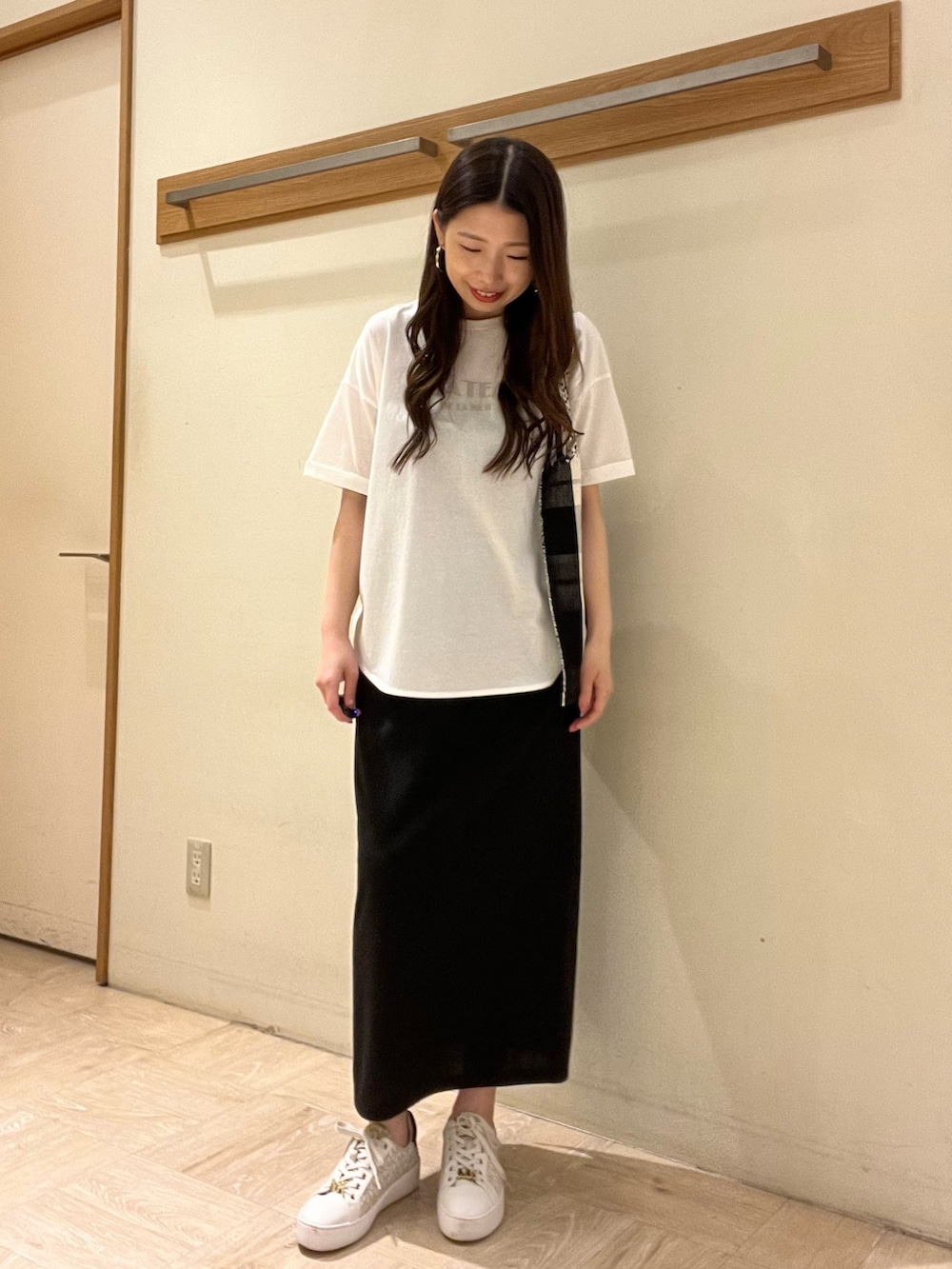 ホワイト系のTシャツ/カットソー、ブラック系のトートバッグ、ブラック系のスカートを着用したレディースの夏コーディネートの3枚目の写真