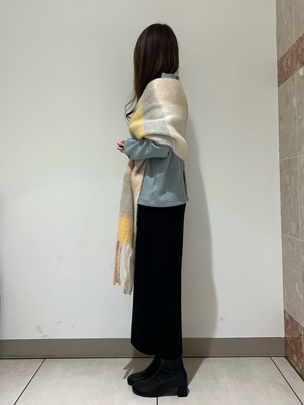 グリーン系のTシャツ/カットソー、ブラック系のスカート、ブラック系のブーツを着用したレディースの冬コーディネートの3枚目の写真