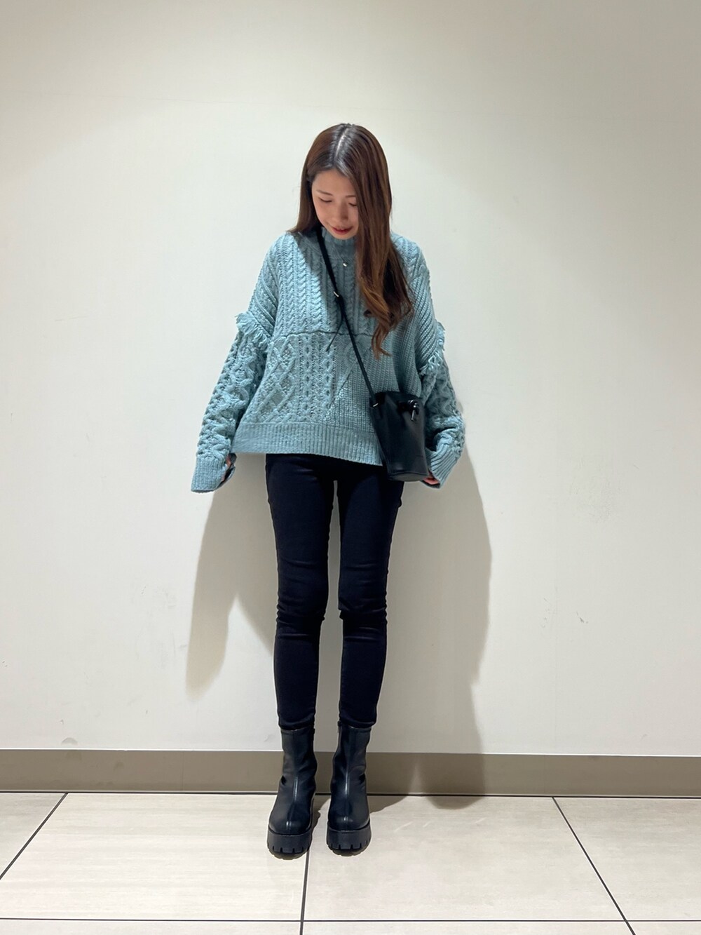 ブルー系のニット/セーター、ブラック系のショルダーバッグ、ベージュ系のストール/ショールを着用したレディースの冬コーディネートの3枚目の写真