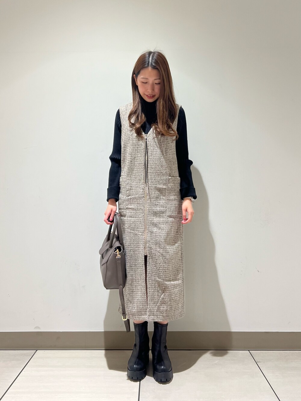 ベージュ系のワンピース、ブラック系のニット/セーターを着用したレディースの冬コーディネートの2枚目の写真