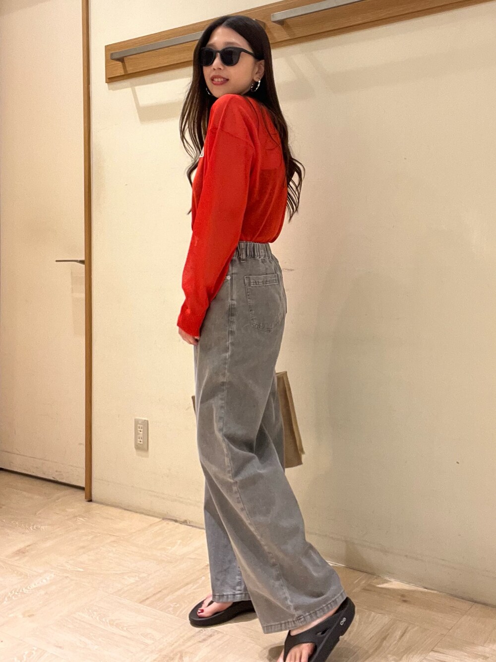 グレー系のデニムパンツ、レッド系のカーディガン/ボレロ、ベージュ系のトートバッグを着用したレディースの春コーディネートの2枚目の写真