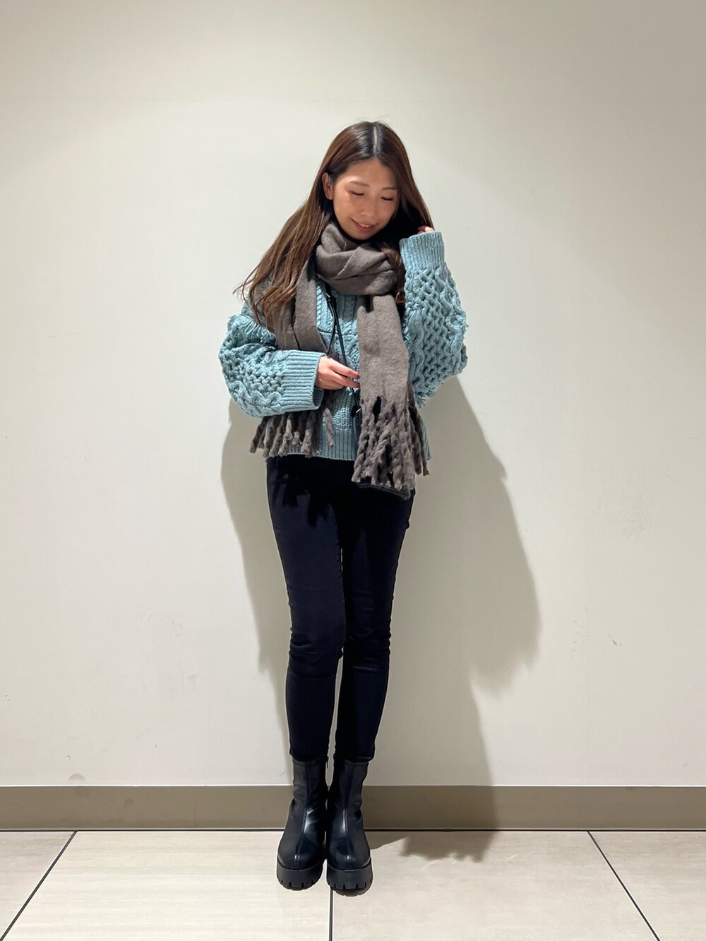 ブルー系のニット/セーター、ブラック系のショルダーバッグ、ベージュ系のストール/ショールを着用したレディースの冬コーディネートの2枚目の写真