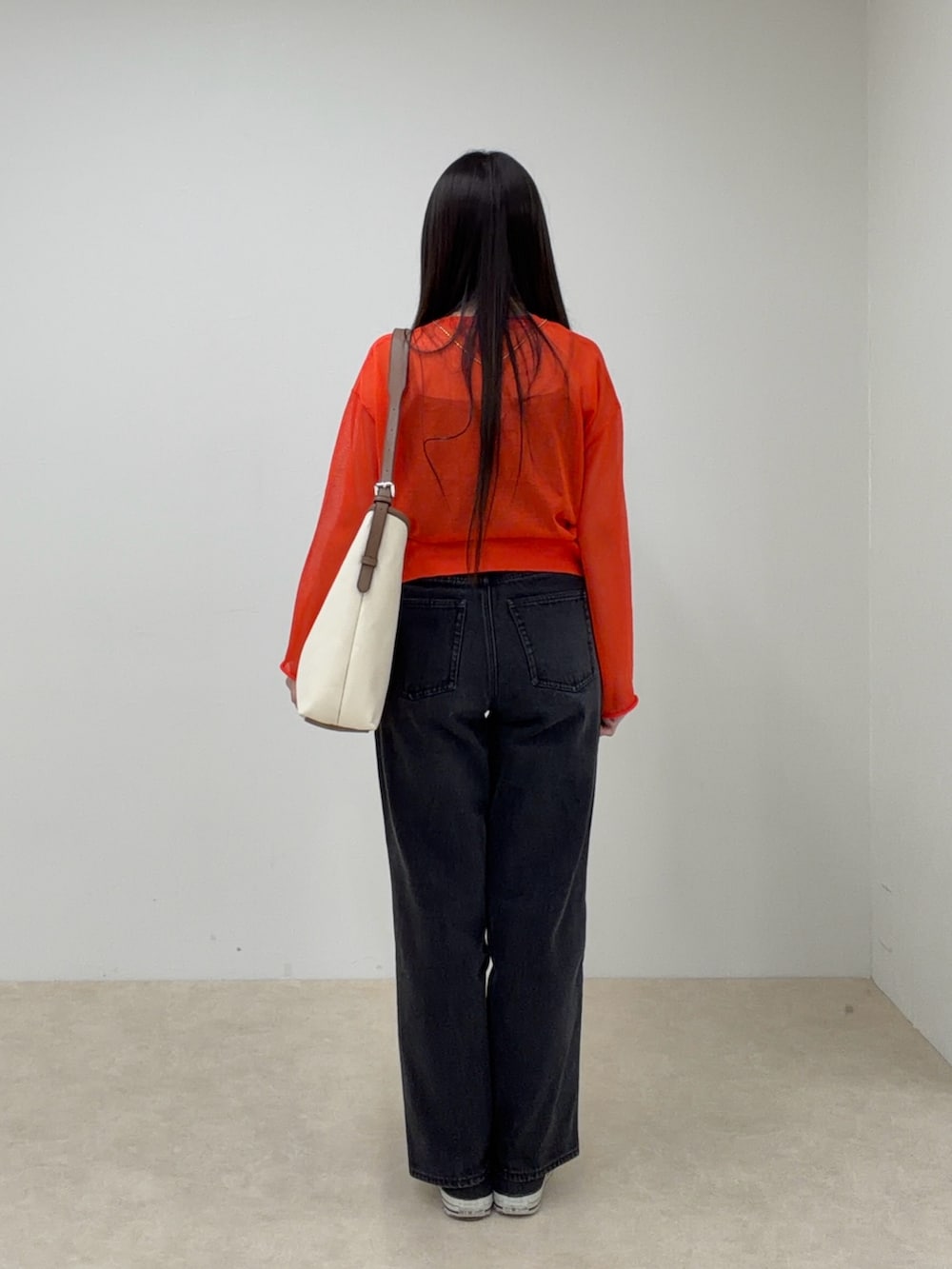 オレンジ系のカーディガン/ボレロ、ホワイト系のショルダーバッグ、ブラック系のデニムパンツを着用したレディースの春コーディネートの3枚目の写真