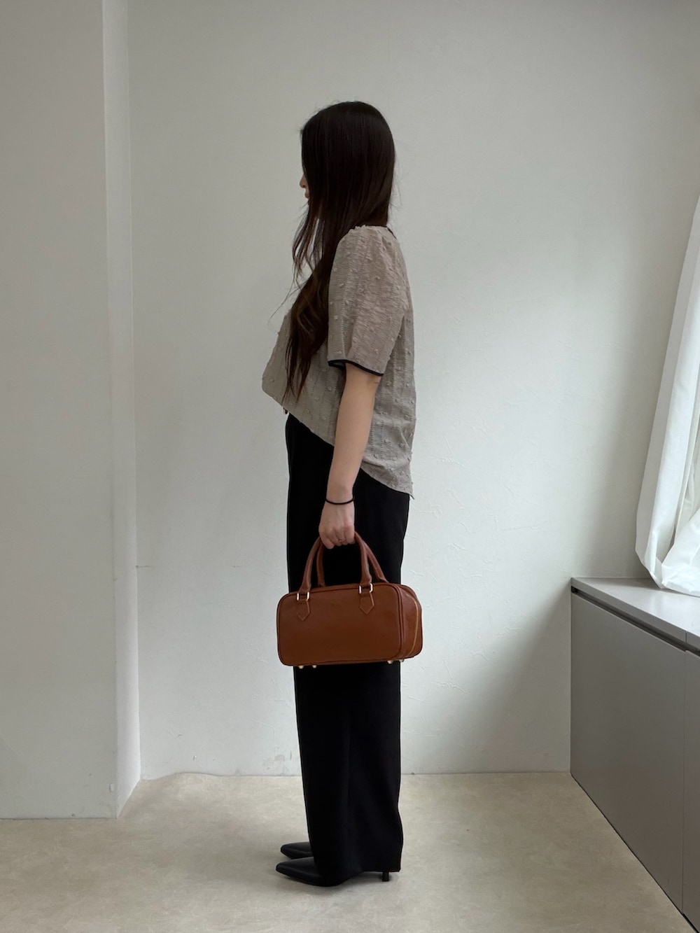 ベージュ系のシャツ/ブラウス、ブラック系のスラックス、ブラック系のパンプスを着用したレディースの春コーディネートの2枚目の写真