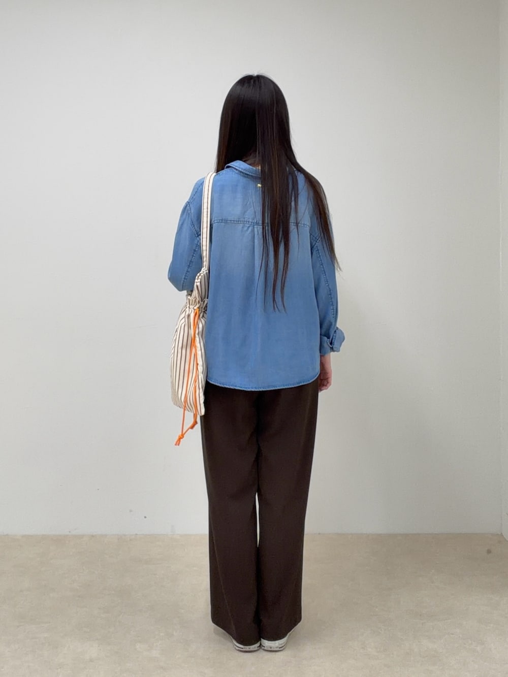 ブルー系のシャツ/ブラウス、ブラウン系のスラックス、レッド系のトートバッグを着用したレディースの春コーディネートの3枚目の写真